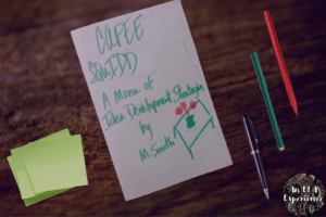 "CAFEE SQuIDD: A Menu of Idea Development Strategies" is written on a folded sheet of paper that sits on a desk.