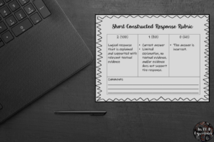 A 0-2 short constructed response rubric is pictured on top of a black desk.