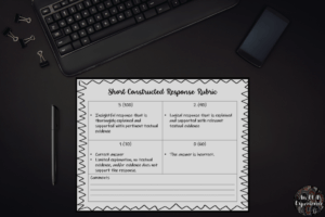 A short constructed response rubric is pictured on top of a black desk.